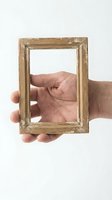 Hand holding empty vintage wooden frame on white background for creative design projects and artistic presentations.