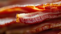 Crispy bacon strips with golden edges and marbled fat layers, perfect for breakfast dishes, cooking ingredients, and food photography projects.