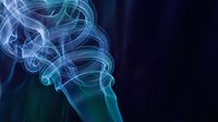 Swirling blue and teal smoke curls gracefully against a dark background, creating an ethereal, mysterious atmosphere for creative projects.