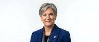 Professional mature Caucasian businesswoman with gray hair in navy blue suit jacket smiling confidently against white background for corporate use.