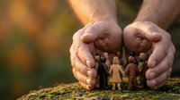 Protective hands sheltering diverse wooden family figures on natural ground, symbolizing care, security, unity and community support in warm outdoor setting.