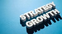 White wooden letters spelling strategy growth on blue background casting shadows for business planning and development concepts.