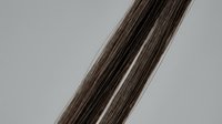 Smooth dark brown hair strands close-up on gray background, showcasing silky texture and natural shine for beauty and haircare concepts.
