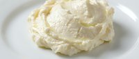 Creamy mashed potatoes with butter on white plate, ready for serving as a side dish or comfort food ingredient.