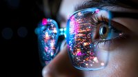 Close-up view of eyeglasses reflecting vibrant city lights and bokeh effects, showing partial face with dramatic eye detail and neon colors in modern urban setting.