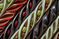 Assorted gourmet chocolate bars with decorative patterns, nuts and dried fruits arranged in rows for confectionery and dessert concepts.