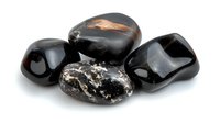 Polished black obsidian and snowflake obsidian stones on white background, natural volcanic glass minerals showing smooth surface and unique patterns.