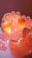 Glowing glass bowl filled with orange slices and pink translucent spheres creating a vibrant fruit arrangement against a warm red background.