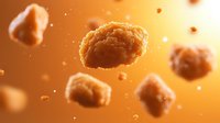 Crispy golden chicken nuggets floating in warm amber light with particles and crumbs suspended in air, creating dynamic food composition for restaurant menu design.