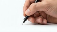 Hand holding black pen ready to write on clean white paper surface for business documentation and creative writing projects.