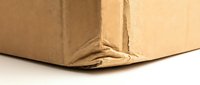 Damaged cardboard shipping box with torn corner showing wear from handling and transportation for packaging and delivery concepts.