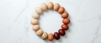 Fresh farm eggs arranged in circular pattern showing natural color variation from white to brown on marble surface for organic food photography and cooking concepts.