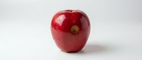 Fresh red apple with glossy skin and stem isolated on white background, suitable for food, nutrition, health and wellness marketing materials.