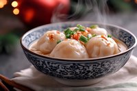 Steaming hot Asian dumplings with chili flakes and green onions served in traditional blue and white porcelain bowl against dark background with bokeh lights.