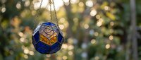 Stained glass ornament with geometric pattern hanging on chain against blurred bokeh lights background for holiday decoration and festive atmosphere.