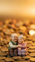 Elderly couple figurines embracing on golden coins with warm bokeh background representing retirement savings and financial security for seniors.