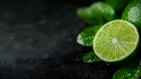 Fresh cut lime with water drops and green leaves on dark moody background, macro food photography for cocktail menu and beverage advertising.