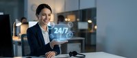 Professional businesswoman presenting 24/7 customer service concept with holographic display in modern office environment for business communication solutions.
