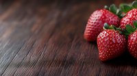 Fresh ripe strawberries on dark wooden rustic background with copy space. Natural lighting creates dramatic mood for food photography and design.
