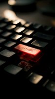 Red illuminated cancel key on black computer keyboard with dramatic lighting and shallow depth of field for business and technology concepts.