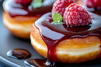 Fresh raspberry donut with chocolate glaze and mint garnish on dark plate, extreme close up macro shot showing texture and dripping sauce.