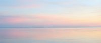 Serene coastal landscape at dawn with soft pink and purple hues reflecting on calm ocean waters, perfect for wellness, travel, and relaxation design projects.