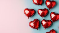 Red heart-shaped foil balloons arranged on pastel blue background. Romantic festive composition for Valentine's Day, wedding or anniversary celebration.
