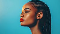 Profile view of young woman with braided hairstyle and bright red lipstick against turquoise background, showcasing modern beauty and fashion styling.
