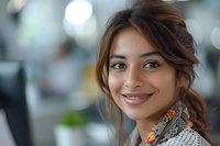 Young mixed race businesswoman with warm smile and casual updo hairstyle in modern office setting with soft bokeh background lighting effect.