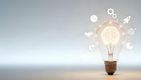 Light bulb with glowing brain filament surrounded by innovation icons on clean background for creative business concepts and startup ideas.