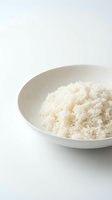 Cooked white rice served in a ceramic bowl on a clean white surface, ready for meal preparation, cooking, and food styling projects.