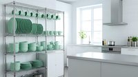 Modern kitchen interior with chrome wire shelving unit displaying mint green dinnerware and dishes in organized storage solution for contemporary home.