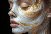 Young Caucasian woman with closed eyes and serene expression wearing artistic white and gold marble-effect face paint makeup on dark background for beauty and fashion concepts.