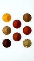 Colorful spice powder collection arranged in circular piles on white background for culinary and cooking applications.