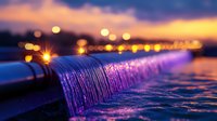 Cascading water illuminated by colorful lights creates mesmerizing pattern at dusk, with bokeh city lights in background. Peaceful urban waterfall scene for relaxation.