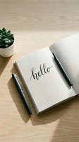 Open notebook with hello calligraphy lettering on wooden desk, pen and succulent plant, minimal workspace flat lay for lifestyle blogs.