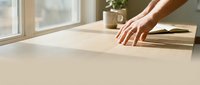 Hand touching smooth wooden surface in bright sunlit room with natural lighting and minimalist interior design for home decor and furniture concepts.