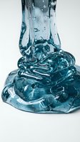 Clear gel or liquid substance pouring and pooling on white background, creating glossy, translucent forms with bubbles and droplets for cosmetic, skincare, or product packaging design use.