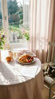 Cozy New Year morning table with champagne, croissant, fresh fruits, Happy New Year card, and a sleeping cat by sunny window.