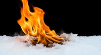 Fire flames burning through white snow on black background creating dramatic contrast for heating, winter, energy concepts.