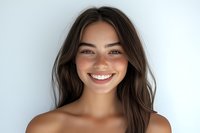 Young Caucasian woman with freckles and natural brown hair smiling genuinely at camera against light background, showing white teeth and radiating happiness and confidence.