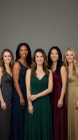 Five diverse women in elegant evening gowns posing together for formal event photography. Professional portrait showcasing friendship and celebration.