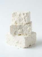 Stacked fresh white cheese blocks isolated on neutral background, suitable for food packaging, culinary blogs, restaurant menus, and dairy product marketing materials.