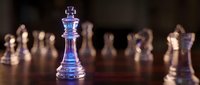 Glass chess king piece standing prominently on wooden board with blurred chess pieces in background, strategic thinking and leadership concept for business.