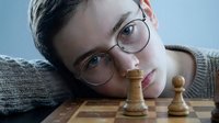 Young man with glasses playing chess, strategic thinking and concentration during board game. Intellectual hobby and mental challenge for leisure time.
