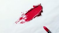 Red lipstick smear with cosmetic tube on white background. Makeup beauty product isolated for design use in advertising and fashion projects.