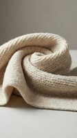 Soft beige knitted wool sweater folded in elegant swirls showcasing cozy texture and warmth for autumn winter fashion and comfort lifestyle concepts.