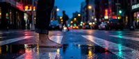 Person walking on wet city street at night with colorful neon lights reflecting in puddles creating vibrant urban atmosphere for lifestyle and travel content.