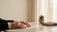 Professional businesswoman hands resting on wooden desk in modern office workspace with natural lighting and minimalist decor for corporate presentations.