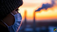 Young woman in knit hat and denim jacket gazing at industrial sunset skyline with factory smokestacks creating atmospheric pollution backdrop for environmental themes.
